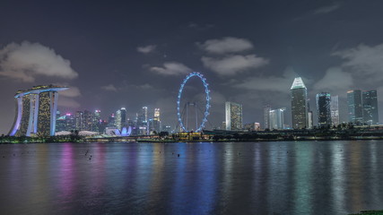 Naklejka premium Downtown skyline of Singapore as viewed from across the water from The Garden East night timelapse. Singapore.