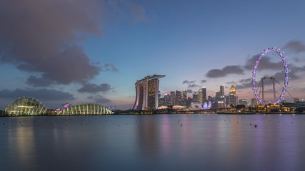 Downtown skyline of Singapore as viewed from across the water from The Garden East day to night timelapse. Singapore.
