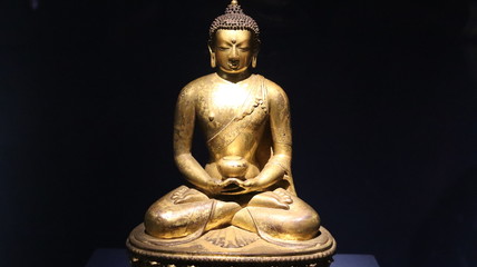 Mumbai, Maharastra/India- March 31 2020: Golden idol of lord Buddha sitting on the ground.