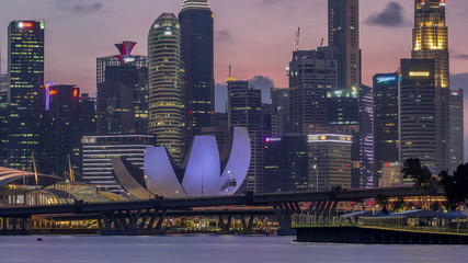 Downtown skyline of Singapore as viewed from across the water from The Garden East day to night timelapse. Singapore.