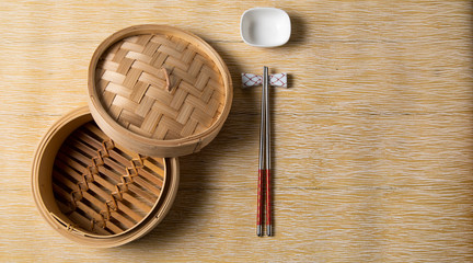 Fototapeta na wymiar Empty basket of dim sum made by bamboo material and chopsticks. Chinese Traditional cuisine concept. Dumplings Dim Sum in bamboo steamer with text copy space. Asian food background