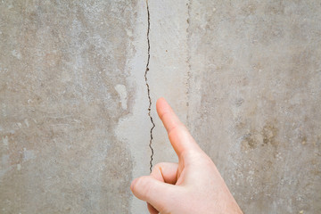 Man hand finger pointing to cracked ceiling. Building problem and solution concept. Close up.