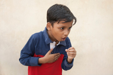 Boy covered mouth with hand, cough, keeping hand on chest