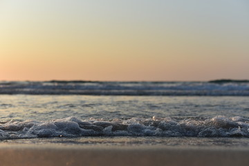 sea surf on the sandy beach at sunset
