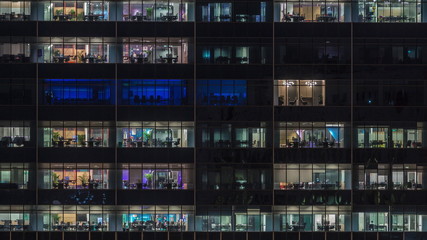 Modern office building with big windows at night timelapse, in windows light shines
