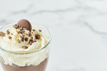 Isolate with copy space chocolate mousse and cream cup for a restaurant menu on white marble background