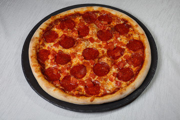 Italian pizza on gray plates on a white plate with spices and seasonings vegetables and meat.
