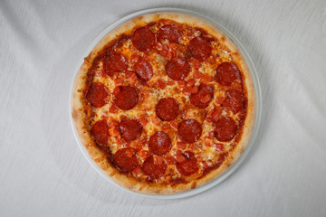 Italian pizza on gray plates on a white plate with spices and seasonings vegetables and meat.