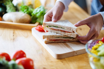 Closeup image of a female chef cooking and holding a piece of whole wheat sandwich in kitchen