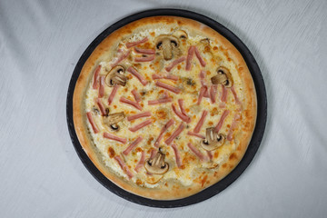 Italian pizza on gray plates on a white plate with spices and seasonings vegetables and meat.