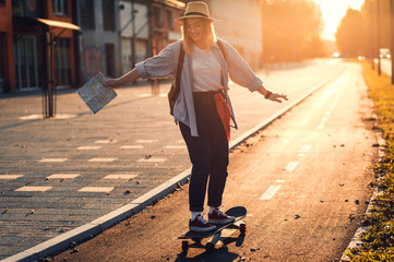 Smiling girl driving long board in the city during sunset.