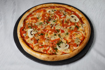 Italian pizza on gray plates on a white plate with spices and seasonings vegetables and meat.