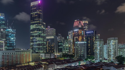 Aerial view of Chinatown with red roofs and Central Business District skyscrapers night timelapse, Singapore