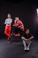 Obraz premium A team of three people poses in a photo studio. bright costumes. on a dark background. creative team.