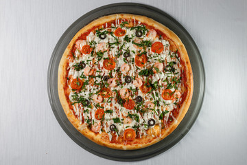 Italian pizza on gray plates on a white plate with spices and seasonings vegetables and meat.