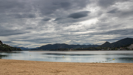 Castro Urdiales beach on a day with gray clouds.
