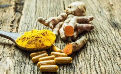 Turmeric capsule and roots curcumin on black background