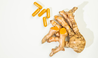 Turmeric powder and fresh turmeric on wooden background.