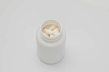 White round tablets covered with a cover are scattered from a plastic can with them. Drugs, pill.