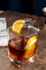 A view of a citrus garnished whiskey drink in a restaurant or kitchen setting.