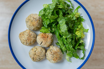 Some baked tuna balls and green salad in a plate.