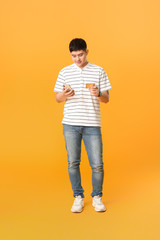 Fototapeta na wymiar Asian man with credit card and mobile phone on color background