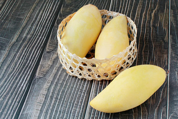 Yellow mango in basket on wood table. Top view. Copy space. Zero Waste