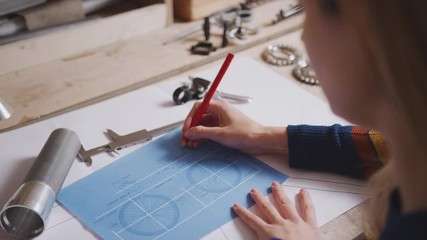 Close up of female engineer in workshop making notes and measuring components for bicycle with micrometer - shot in slow motion