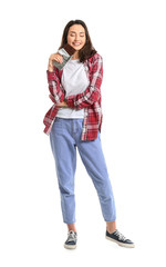 Beautiful young woman eating tasty chocolate on white background