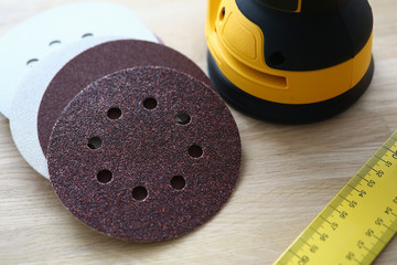 Close-up of sander machine with replacement discs on table. Grinding equipment for renovation and...