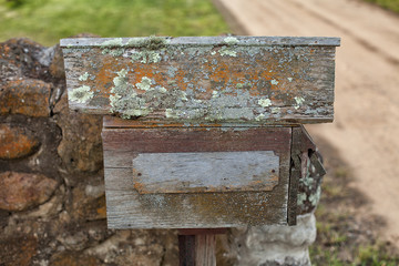 Old wooden letterbox in front of stone wall