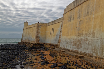 A close up of the thick stone ochre plastered walls of the Sao Sebastiao Fort at the waters edge of...