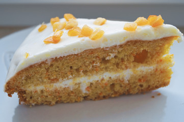 Eating dessert sweets are a carrot cake with a white creamy cream and candied fruits on a white plate