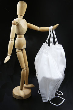wooden mannequin with masks like protestion against corona virus on the black background
