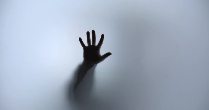 Silhouette of a hand approaching from blur and puts a palm on the screen