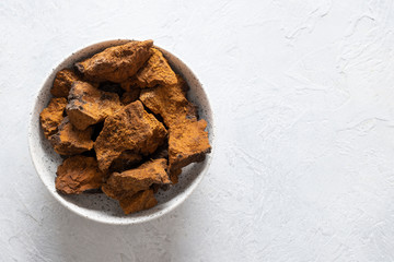 Chaga Birch Mushrooms in bowl on light table. Trendy healthy superfood for infusion, tea or coffee. Copy space.