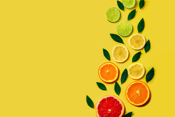 Pattern of citrus lemon, lime, orange and grapefruit slices and mint herbs on yellow background. Top view. Minimal design background.
