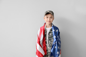 Cute little soldier with USA flag on light background