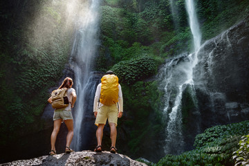 Couple travelers with backpacks are enjoying big waterfall