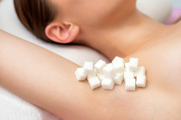 Cubes of white sugar on armpit of woman close-up. Concept of epilation.