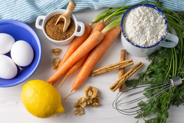 Aerial view of ingredients for carrot sponge cake, on white wooden table, horizontal