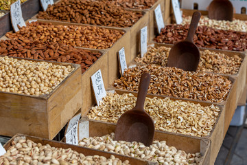 Variety of nuts in tray at food market, shallow depth of field, selective focus on almonds, blurred cashew nuts and pistachio on foreground, blurred nuts on background