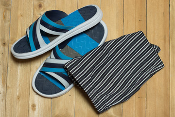 beach accessories, slippers and swimsuit on wooden background