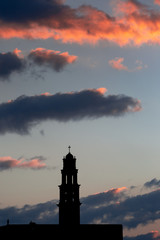 Silhouette of catholic church on dusk cloudscape, rose-colored clouds on purple sunset sky