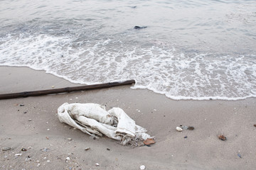 Dirty sand shore with plastic sack, Environmental pollution