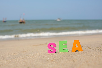 Fototapeta na wymiar Colorful Letters ‘ SEA’ on sandy seashore in holiday summer