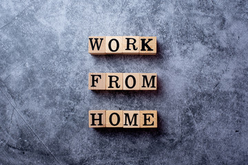 The word WORK FROM HOME on wooden block and placed on black cement background, coronavirus or covid-19 situation