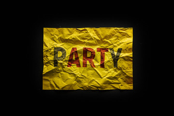 The word party on crumpled yellow paper. Abbreviation. The highlighted letters. Dark background.