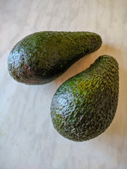 Two green avocados on the table. Close-up. Background.