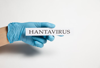 Hand in a medical glove holds a hantavirus tablet on a white background - 334973918